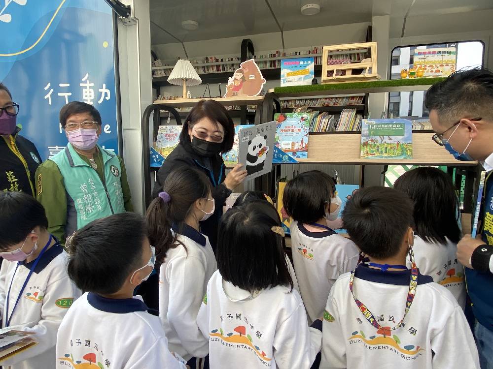 文化局長陳佳君協助學童拿取書車上的繪本
